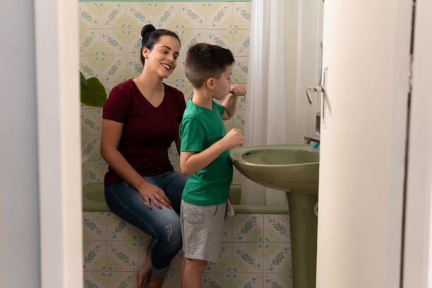istock Child brushes teeth and mother accompanies 1583200120