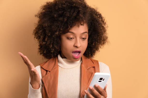 istock surprised woman looking at mobile phone 1583204212