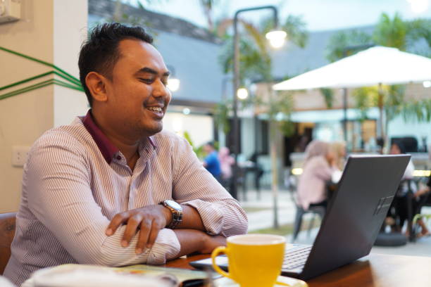 istock Young Asian man using laptop at cafe 1583206261