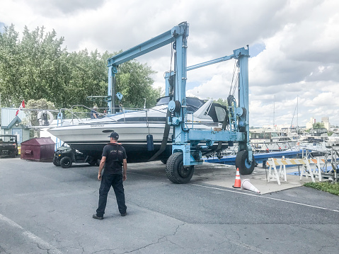 Yacht being lift out of water at marina during summer day
