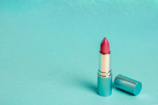 Red lipstick isolated on a blue shiny background, copy space