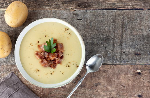 Creamy potato soup with bacon, croutons, ingredients on a wooden background. Top view. Copy space. French vichyssoise soup.