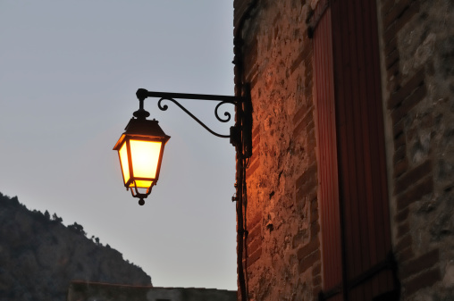 Lighted lamp post at dusk, in the city of Villefranche de Conflent, in the Pyrenees region (French Catalonia)