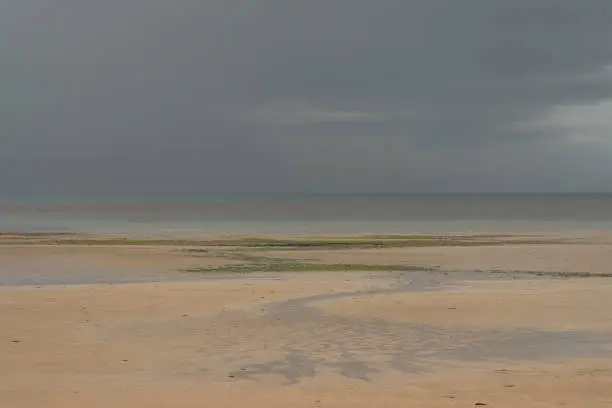 View of a cloudy rainy sky above the sea from the beach