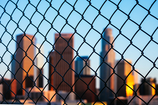 Downtown Los Angeles seen through fence at sunset time. California, USA