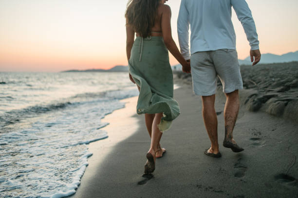 Rear view of a couple walking by the sea in a romantic atmosphere