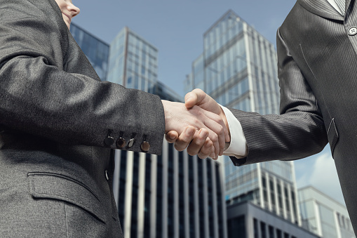 Businessmen shake hands with each other in the background of the business center.