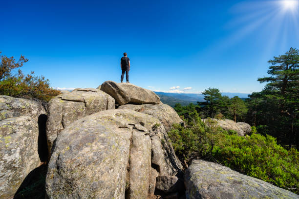 homem em pé no topo de uma grande rocha contemplando a paisagem montanhosa em guadarrama, madrid. - men on top of climbing mountain - fotografias e filmes do acervo