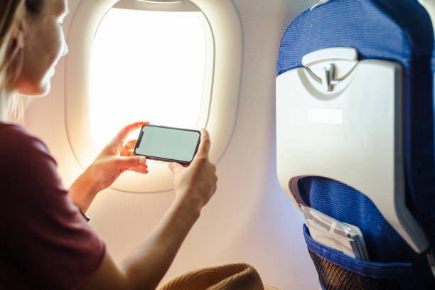 istock Young woman using smart phone in passenger airplane 1583318804