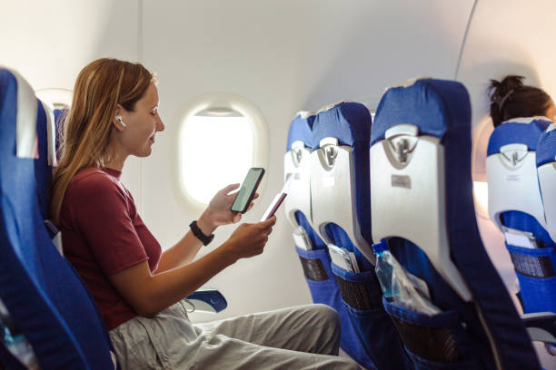 istock Young woman travelling in airplane using smart phone 1583320427