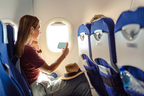 istock Woman in the aircraft holding smart phone with white screen 1583322607