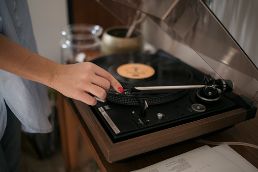 Close-up of a female dropping needle in vintage record on turntable. Close-up of a woman puts a record on a gramophone to listen to classical music.