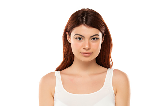 Portrait of serious beautiful woman with long straight ginger hair on a white studio background