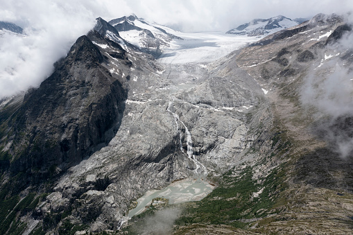 Glacier running into a dirty lake surrounded by rocky landscape