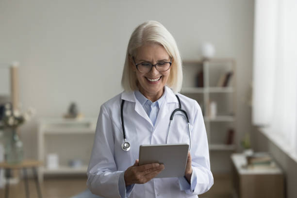 istock Happy focused senior doctor woman using online medical application 1583407521