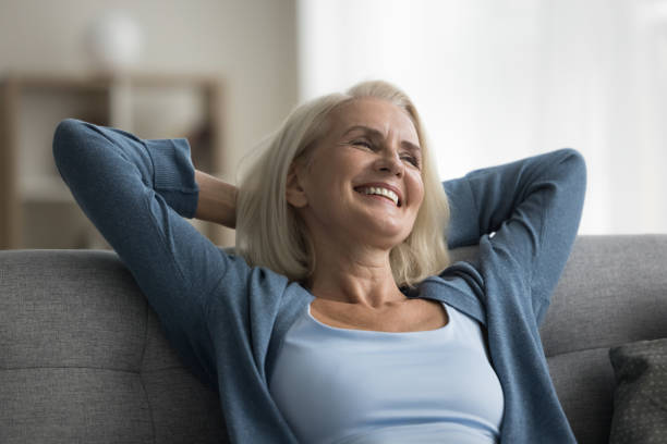istock Cheerful retired elderly woman resting on home couch 1583408549