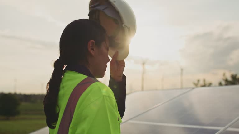 Close-up of Female engineer putting a construction helmet on Solar farm at sunset