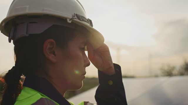 Close-up of Female engineer putting a construction helmet on Solar farm at sunset