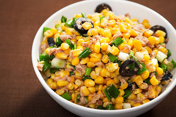 Salad with tuna fish, white corn, olives, green onions and olive oil in a salad bowl