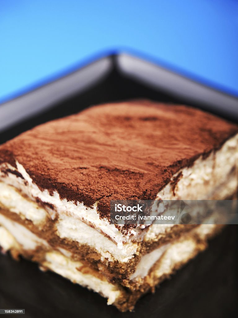 Tiramisu Tiramisu cake in a black plate, close up Blue Background Stock Photo