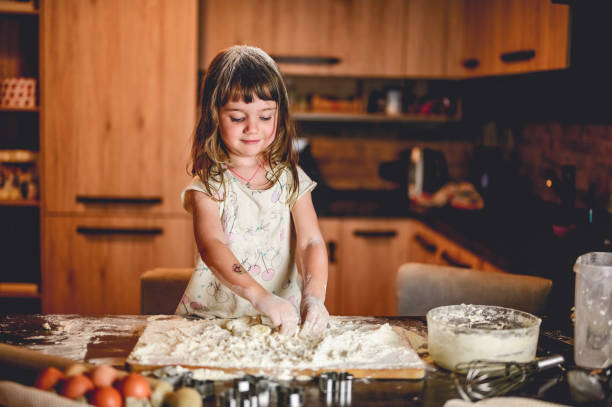 istock little girl playing with the flour in a kitchen. 1583445373