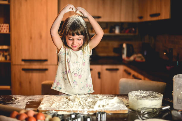 istock little girl throwing flour in a kitchen. 1583445637