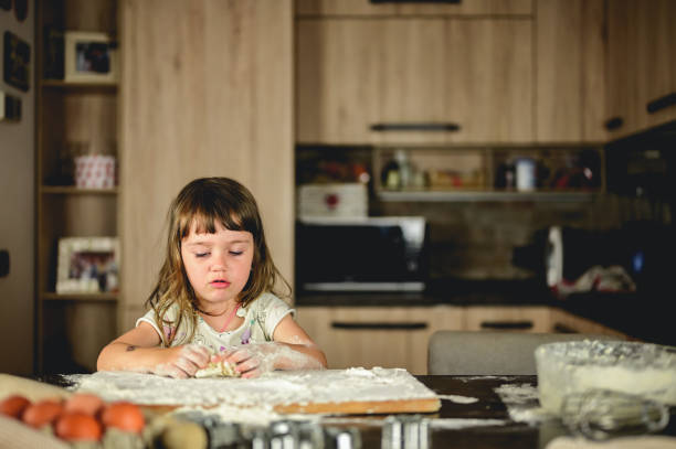 istock little girl playing with the dough for pizza. 1583446412