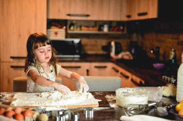 istock little girl playing with the flour on the kitchen table. 1583446416