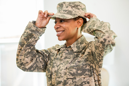 The young adult female soldier proudly adjust her uniform cap before leaving the building.