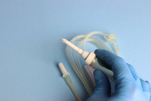 istock Infusion set beeing hold by a professional wearing gloves with a light blue background 1583463108