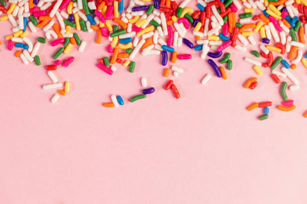 istock Colorful sugar sprinkles on pink background 1583472442