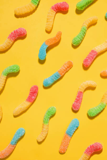 istock Gummy worms assorted candies on bright yellow background, 1583472443