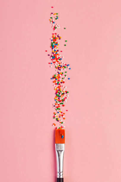 istock Star shaped sugar sprinkles and paint brush on pink background, art and creativity concept 1583472967