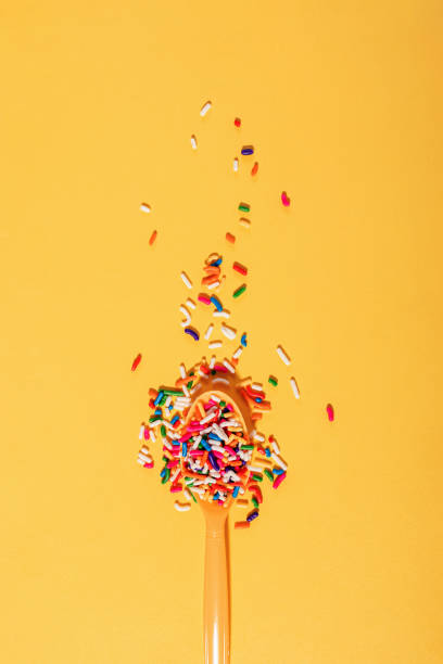 istock Colorful sugar sprinkles in a plastic spoon on bright yellow background, sugar in diet 1583473627