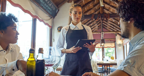 istock Waitress Holding Digital Tablet Listening to Customer 1583502244