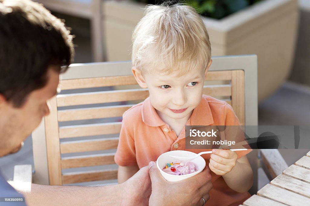 family in outdoor cafe father and his son eating ice-cream in outdoor cafe Adult Stock Photo