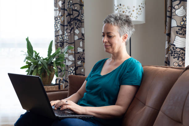 istock Beautiful woman sitting on sofa with laptop 1583514687