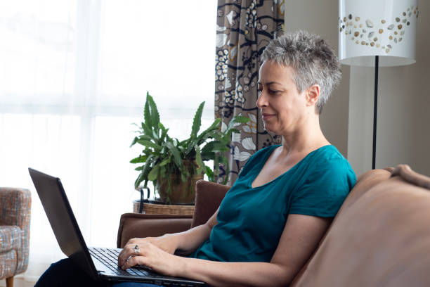 istock Beautiful woman sitting on sofa with laptop 1583516771