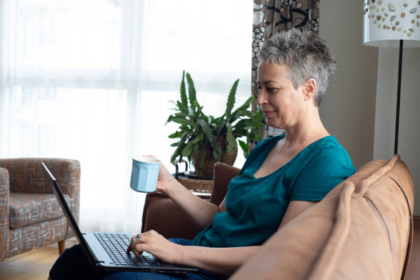 istock Beautiful woman sitting on sofa with laptop 1583517286