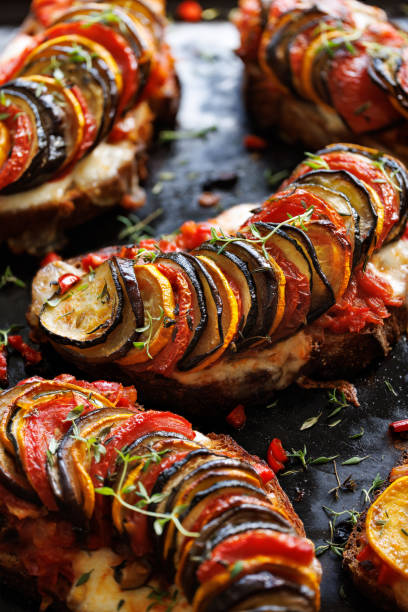 istock Grilled sourdough bread open faced sandwich with sliced vegetables on a black background, close up 1583543188