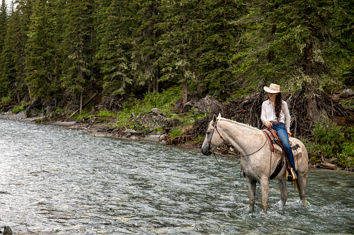 She crosses a wild river in the majestic Canadian Rockies
