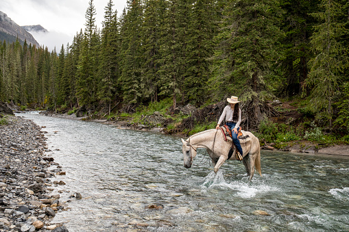 She crosses a wild river in the majestic Canadian Rockies