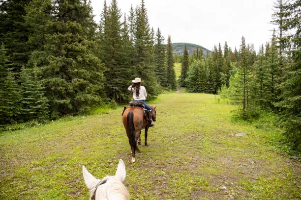 Photo of POV past horse rider to woman horse rider in forest