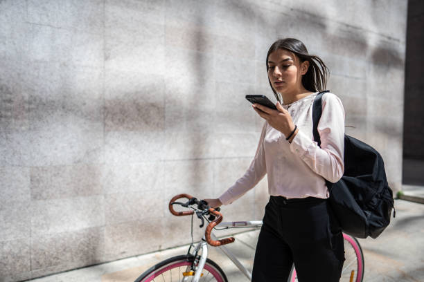 young woman sending a voicemail while walk carrying the bicycle in the city - vocoder imagens e fotografias de stock