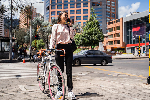 Young man talking on mobile phone while carry the bicycle in the city