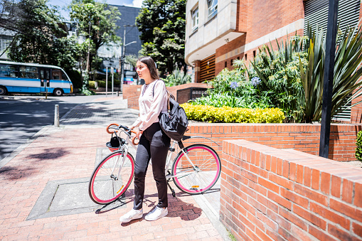 Young woman walking while while walk carrying the bicycle in the city