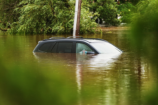 After a river overflows from record-breaking rainfall, a vehicle sits in deep water.