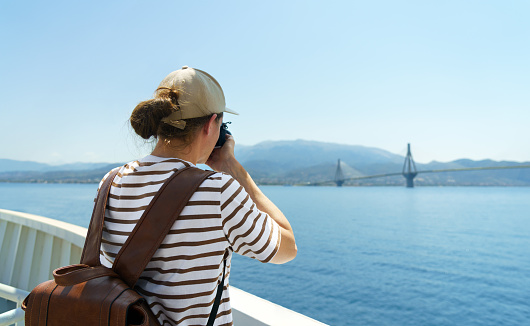 Man photographer with big backpack taking photo of the sea from the ship. Travel and hobby concept