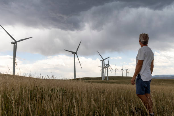 istock Senior man looks towards wind turbines, mountains distant 1583635568