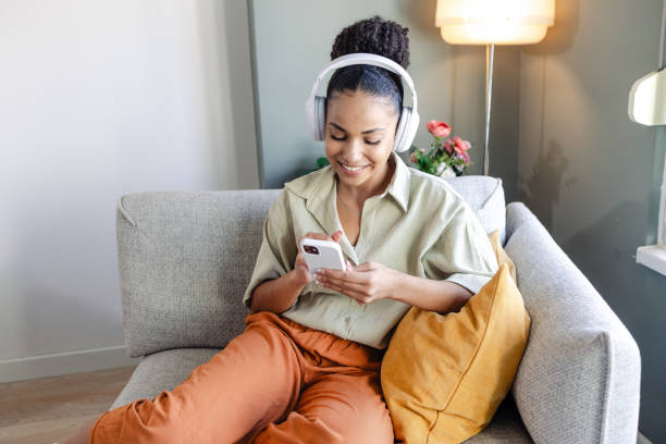 istock Young woman creating a music playlist while listening to music on the smart phone 1583663876